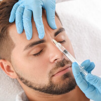 Adult male getting botox injected into forehead.