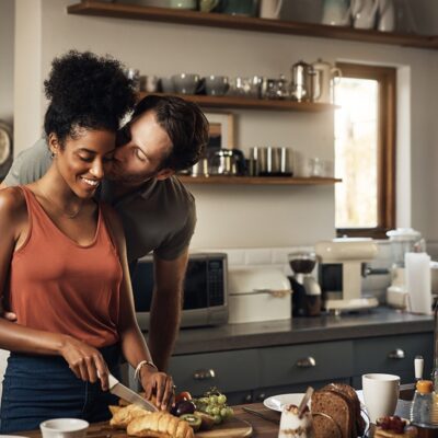 Male warmly kissing his female partner in a home kitchen.